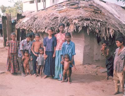 Children standing near a damaged home during post-tsunami community recovery